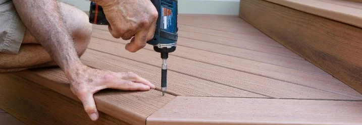 Person baut Holzterrasse mit Akkuschrauber